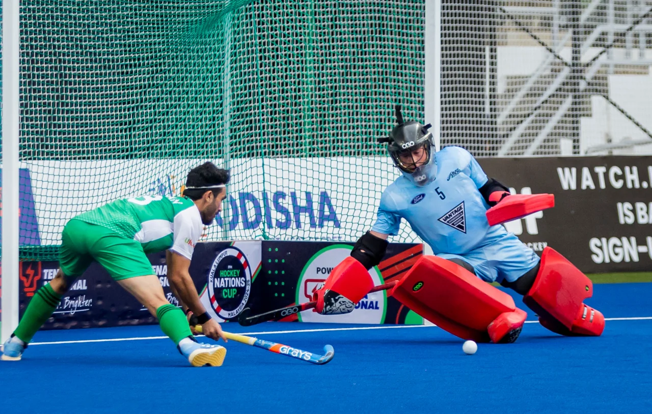 Field hockey goalkeeper in full protection defending the goal in a match