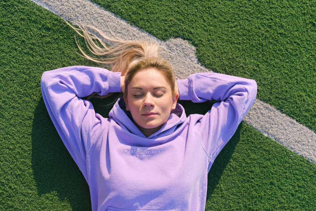 woman laying on a hockey pitch, thinking about why field hockey is the best sport in the world